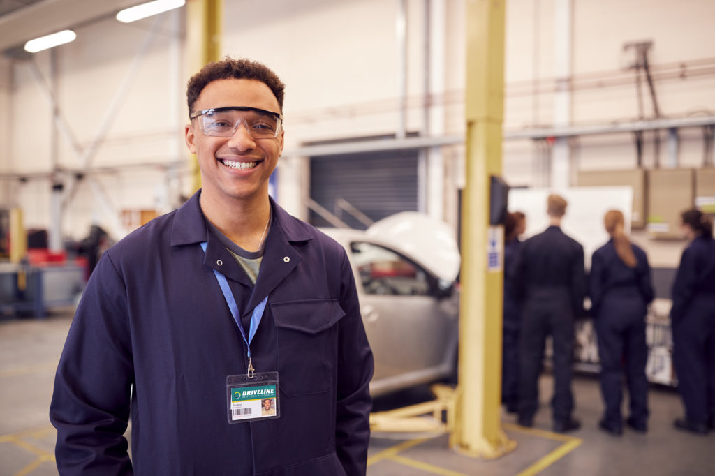 Mechanic standing in workshop with vehicle on hoist | Driveline Services Australia