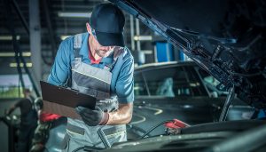 Vehicle mechanic with a clipboard checking vehicle engine | Driveline Services Australia