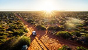 4wd driving in the outback with the sun setting in the background
